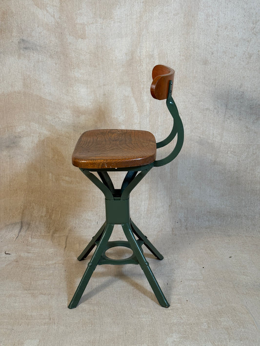 Vintage industrial machinist chair with green steel frame, wooden seat.