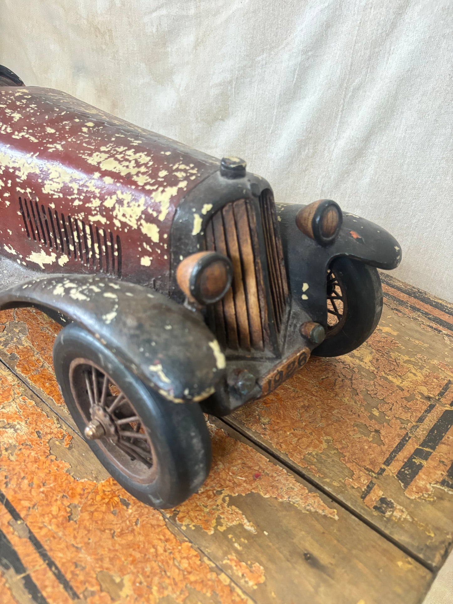 Vintage toy car on a wooden surface with a white background
