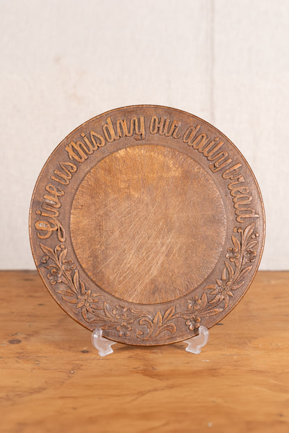 Vintage wooden bread board carved with “Give Us This Day Our Daily Bread” and a decorative floral and wheat motif around the rim.