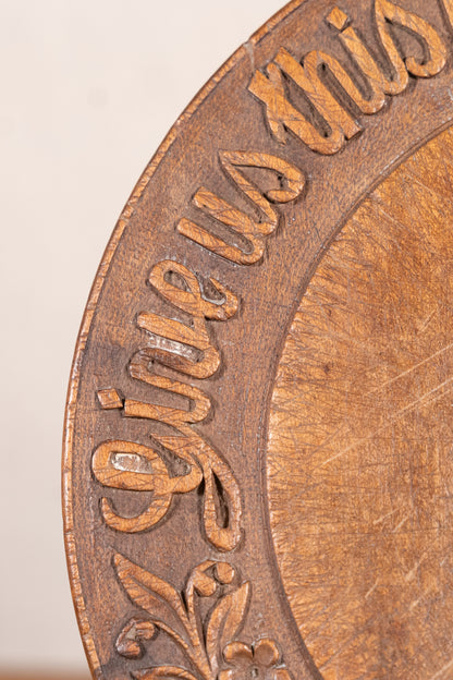 Vintage wooden bread board carved with “Give Us This Day Our Daily Bread” and a decorative floral and wheat motif around the rim.