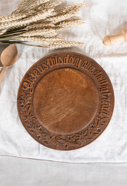 Vintage wooden bread board carved with “Give Us This Day Our Daily Bread” and a decorative floral and wheat motif around the rim.