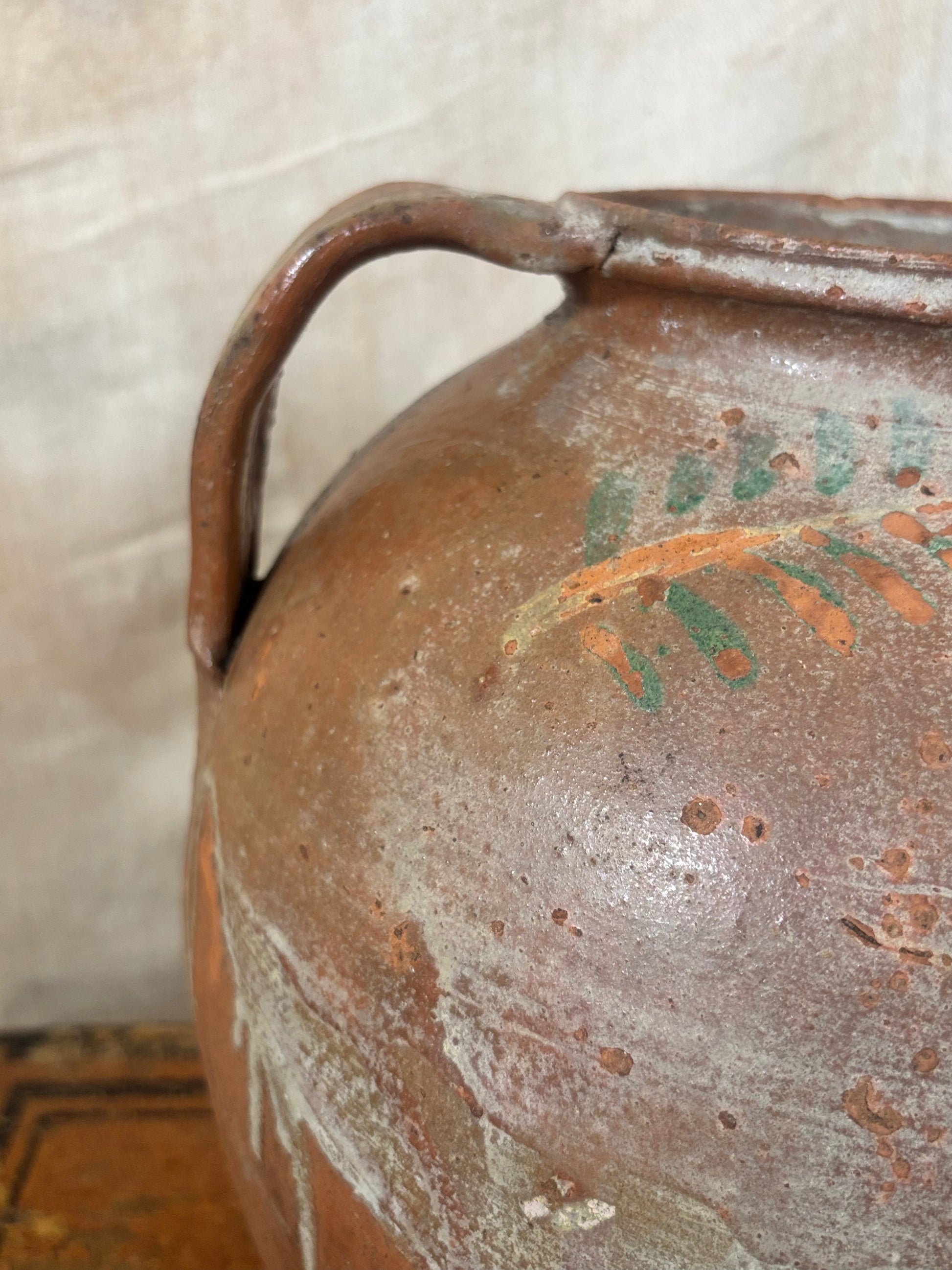 Close-up of a ceramic jar with floral design on a textured surface