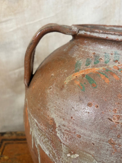 Close-up of a ceramic jar with floral design on a textured surface