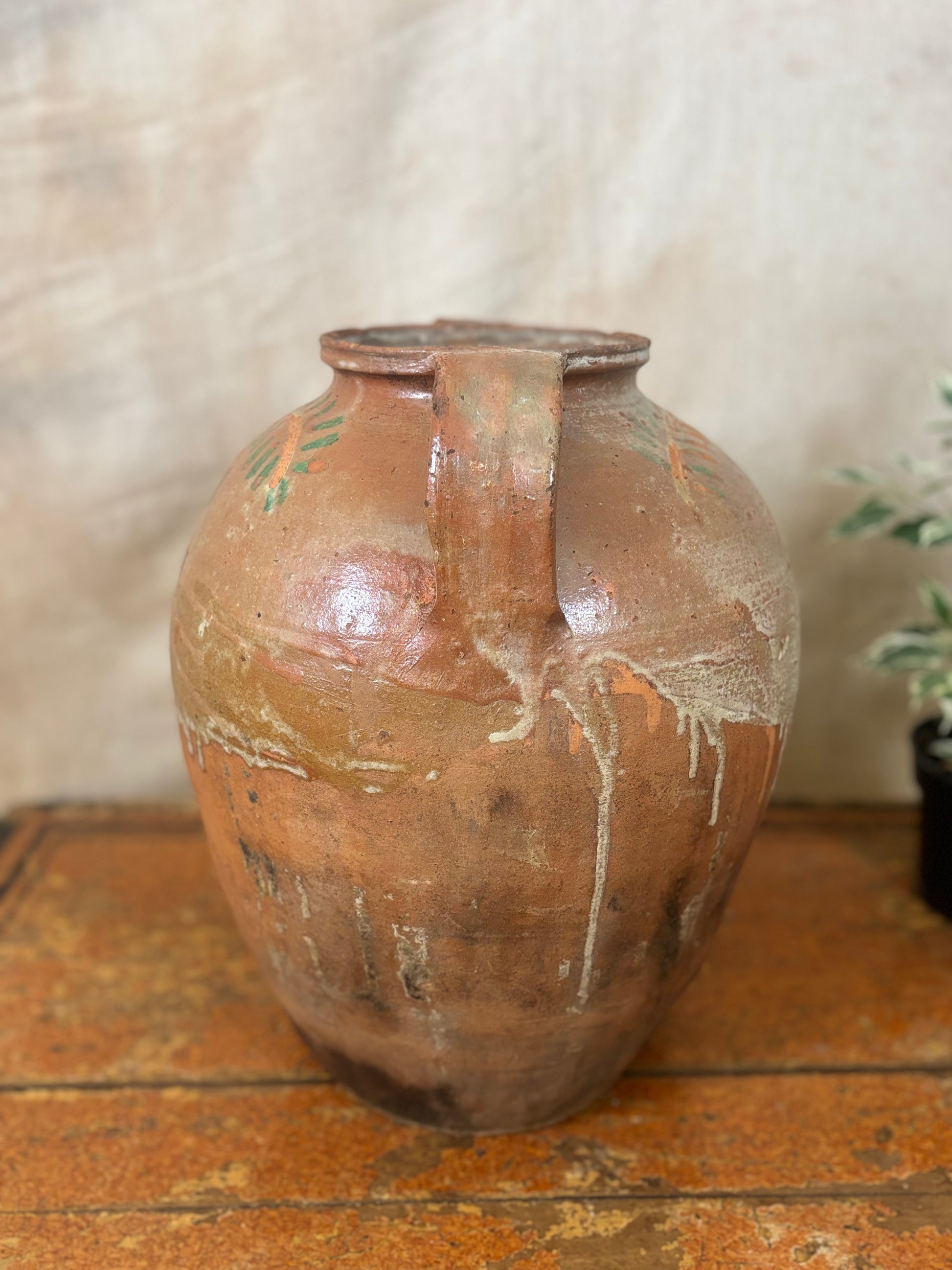 Brown ceramic vase with a handle on a wooden surface