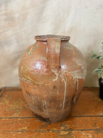 Brown ceramic vase with a handle on a wooden surface