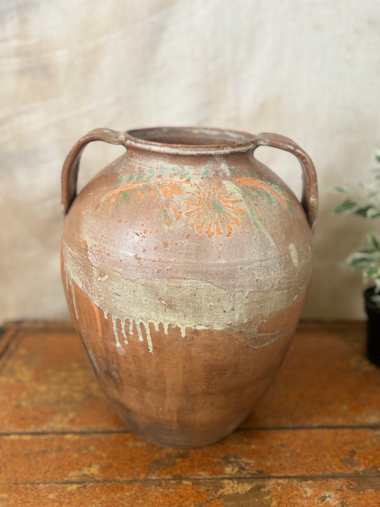 Vintage ceramic jar with handles on a wooden surface