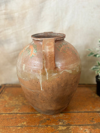 Brown ceramic vase with a handle on a wooden surface