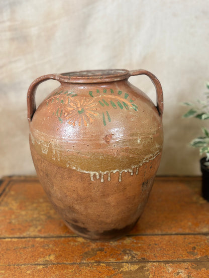 Vintage terracotta vase with handles on a wooden surface