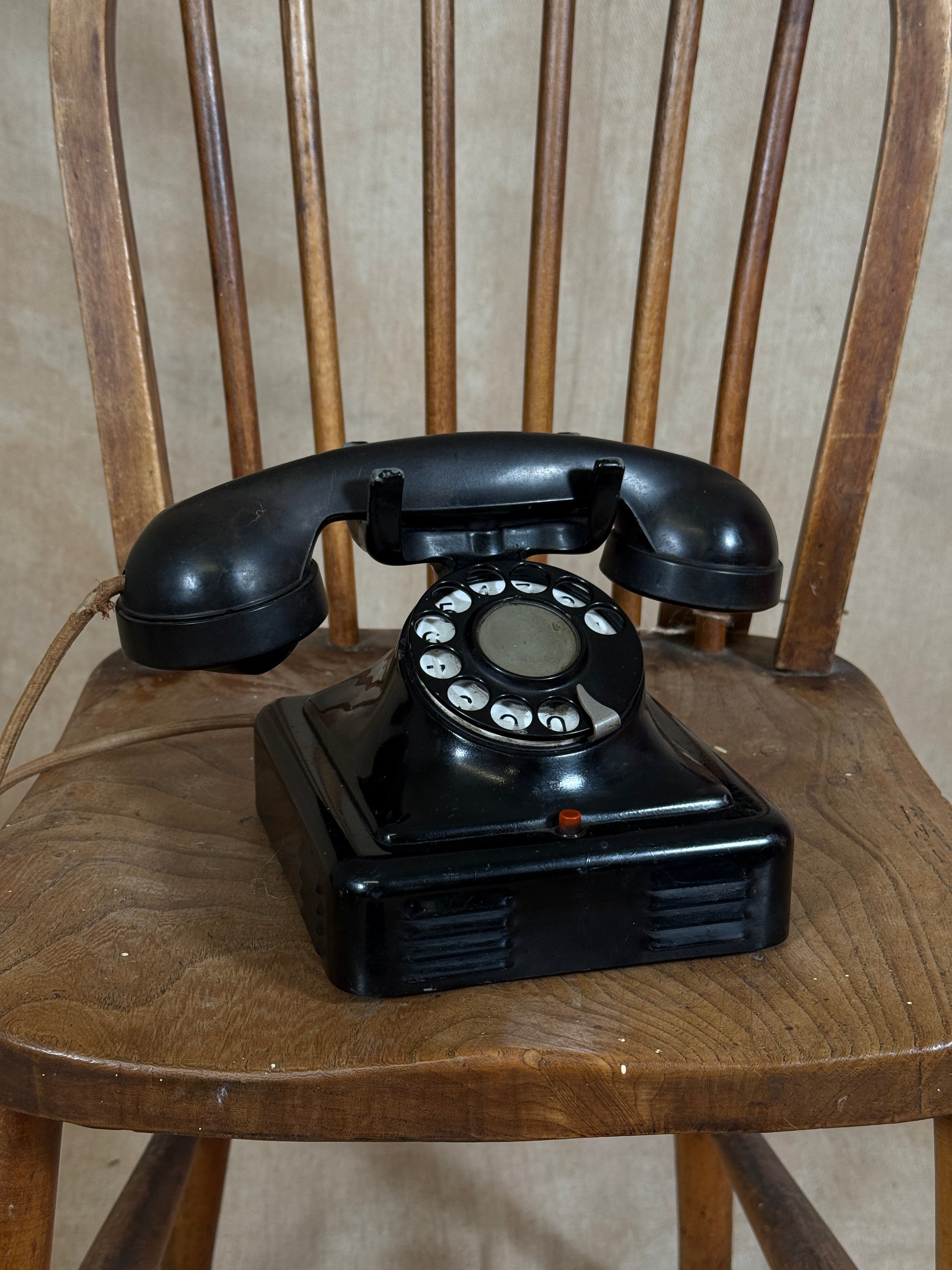 Vintage black rotary phone on a wooden chair