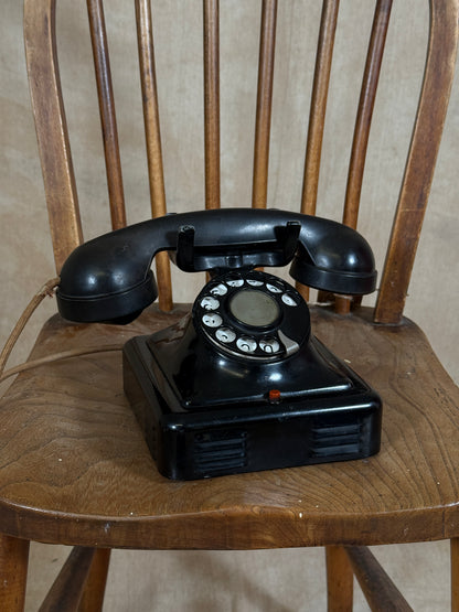 Vintage black rotary phone on a wooden chair