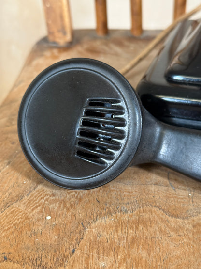 Black hair dryer nozzle on a wooden surface
