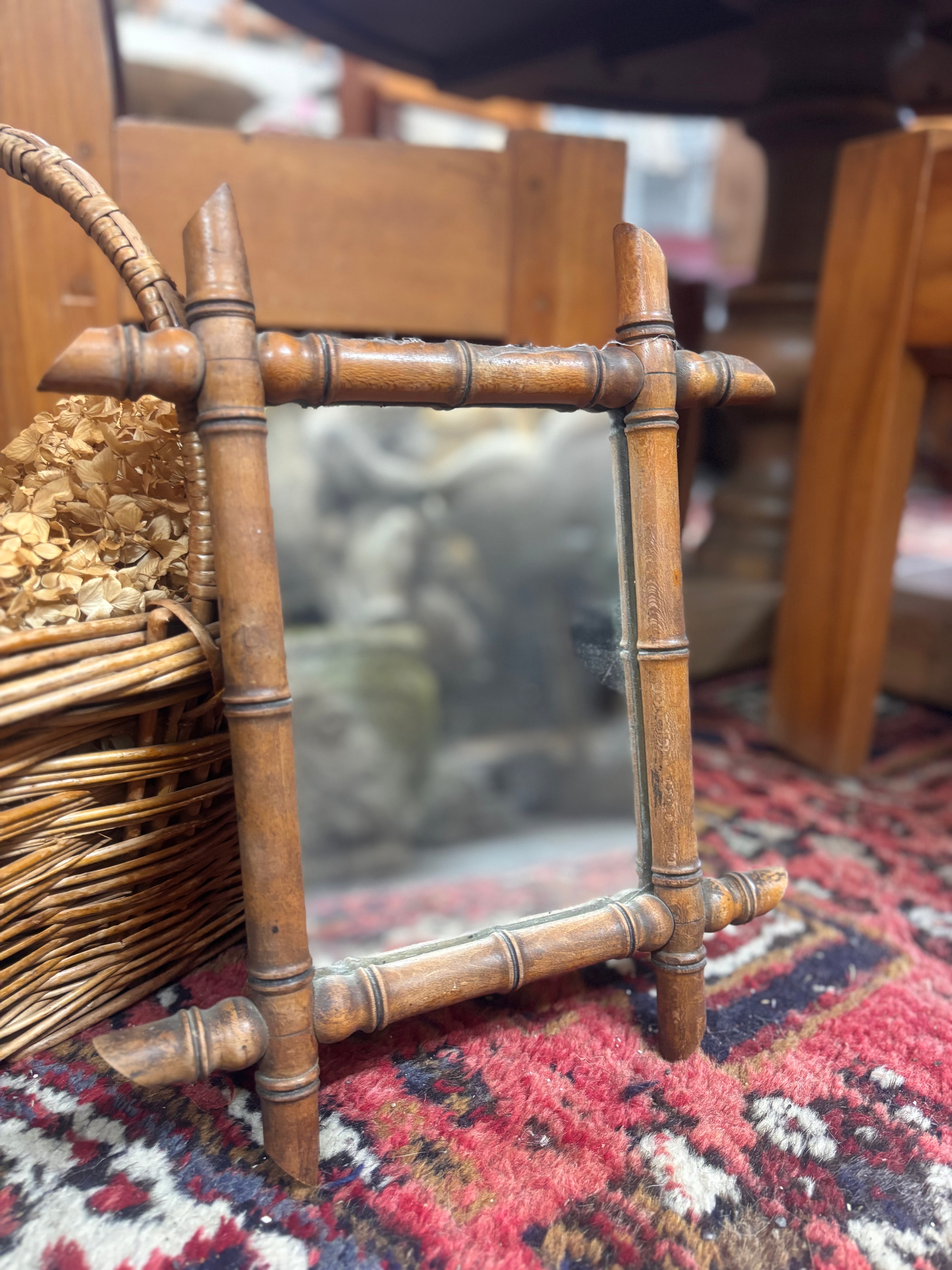 Small bamboo-style mirror on a patterned rug with a blurred background