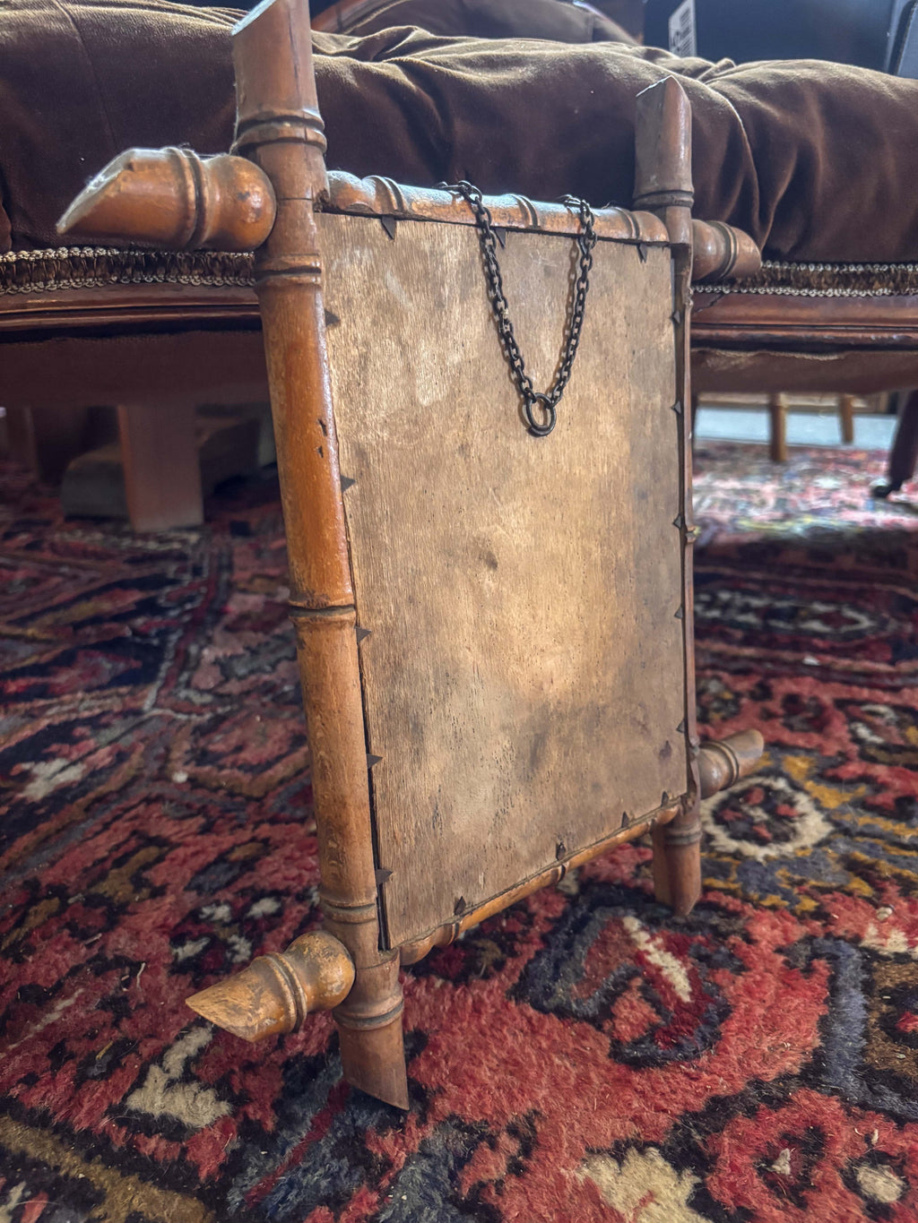 Back of a bamboo Mirror with hanging chain on acolourful rug