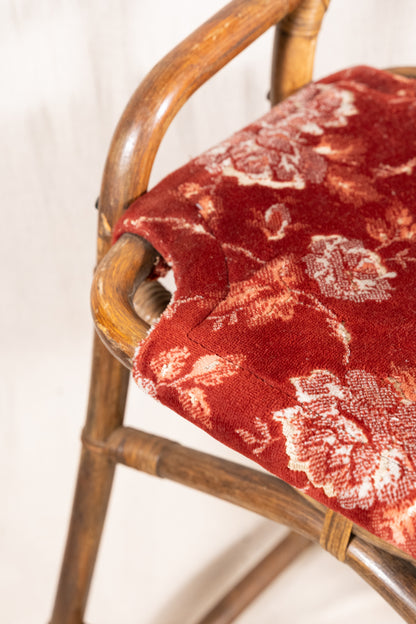 Pair of vintage bamboo bar stools with dark finished frames, red patterned velvet-style upholstery, X-shaped cross supports and lower footrests.