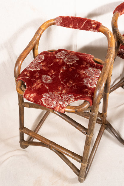 Pair of vintage bamboo bar stools with dark finished frames, red patterned velvet-style upholstery, X-shaped cross supports and lower footrests.