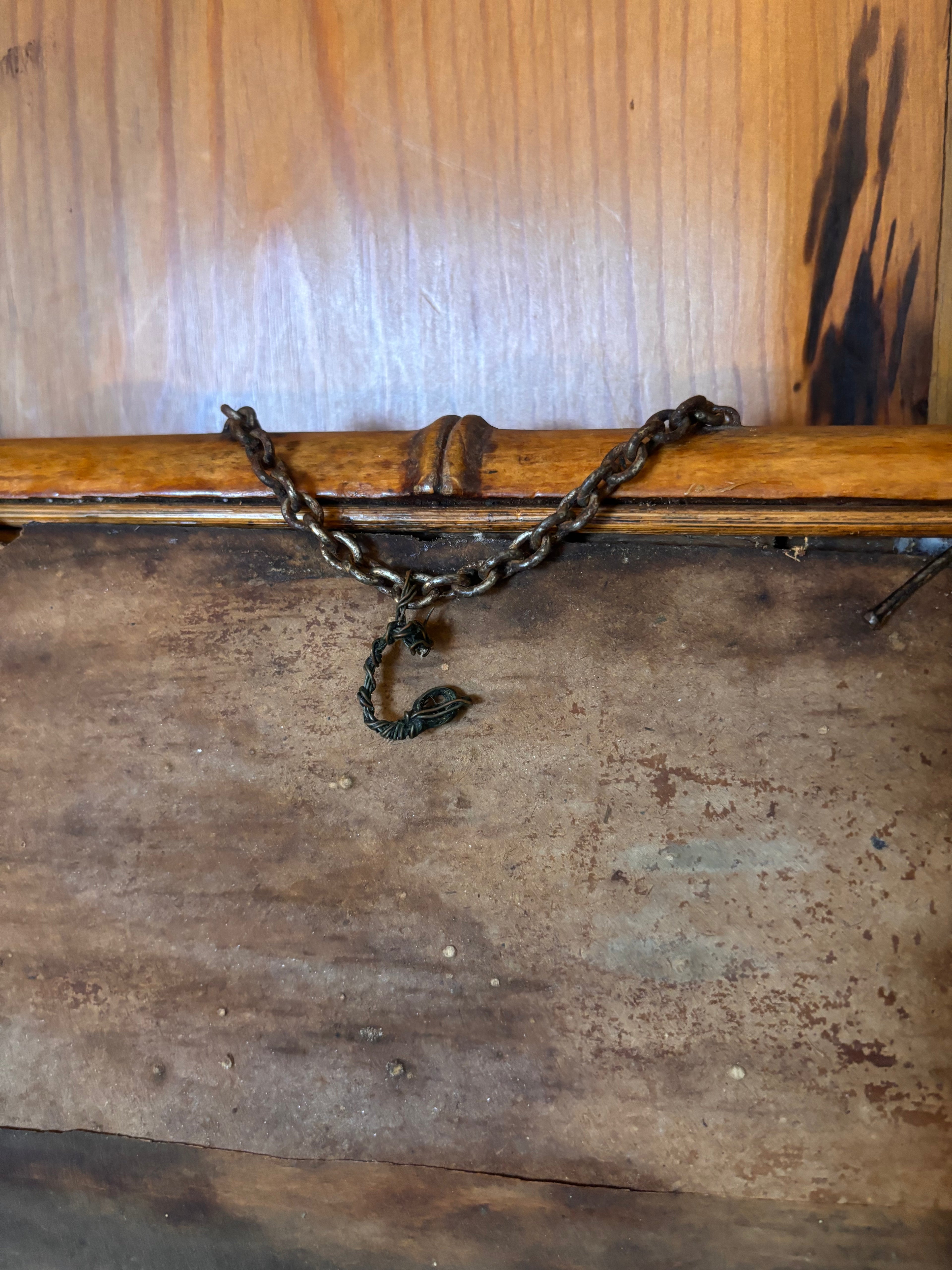 Wooden stick with a chain attached against a wooden background