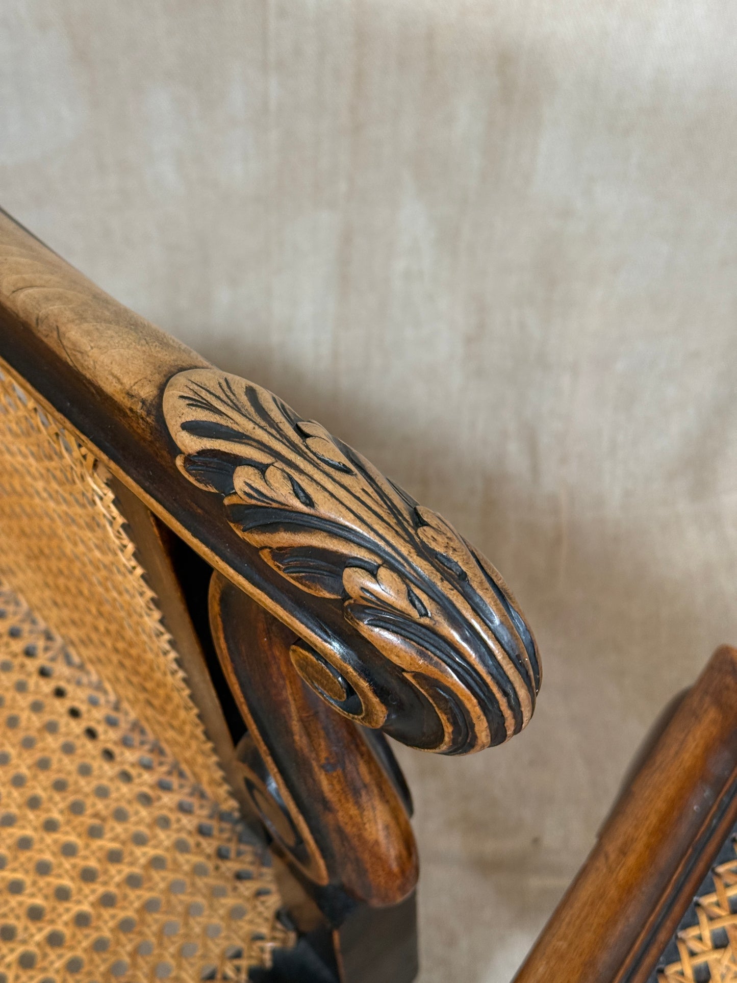 Antique Bergère style cane armchair and matching footstool with dark carved wooden frames and woven cane panels.