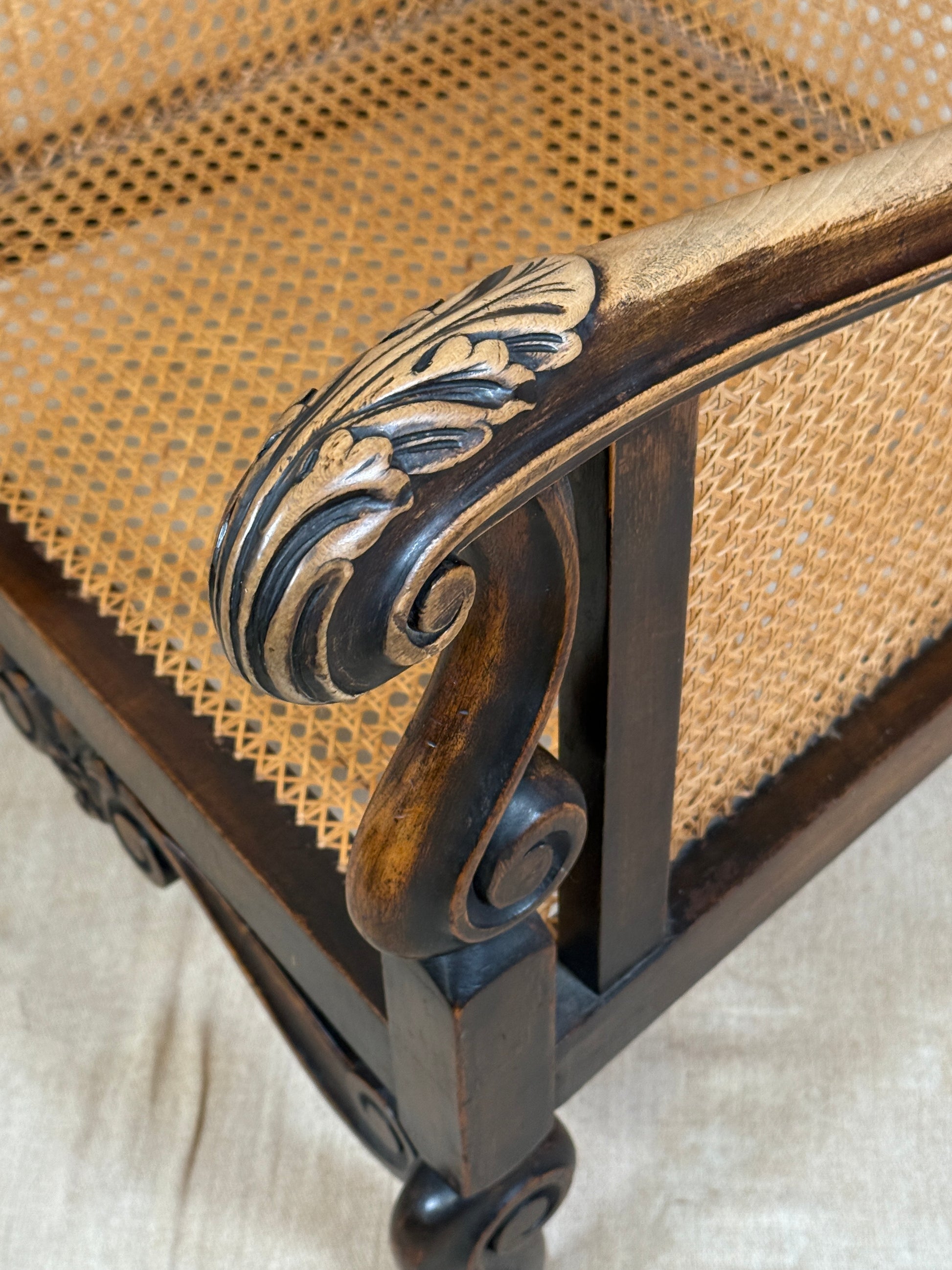Antique Bergère style cane armchair and matching footstool with dark carved wooden frames and woven cane panels.