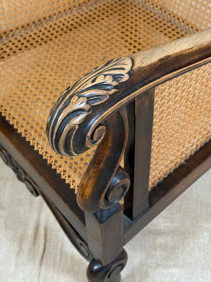 Antique Bergère style cane armchair and matching footstool with dark carved wooden frames and woven cane panels.