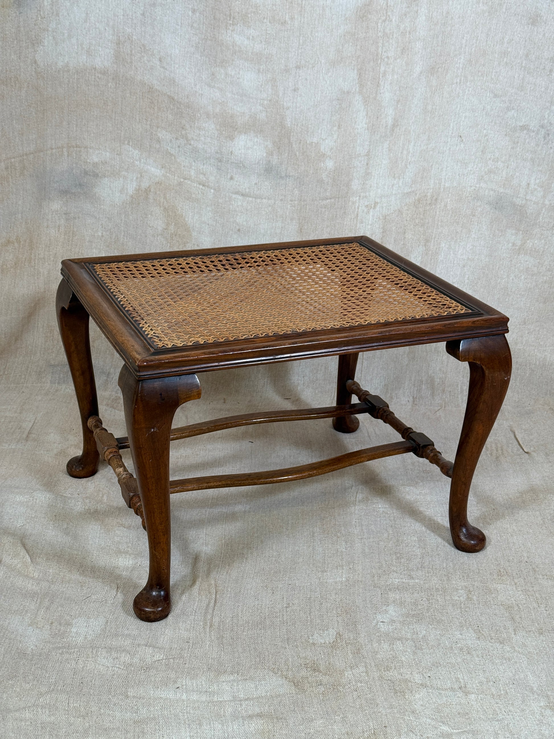 Antique Bergère style cane armchair and matching footstool with dark carved wooden frames and woven cane panels.