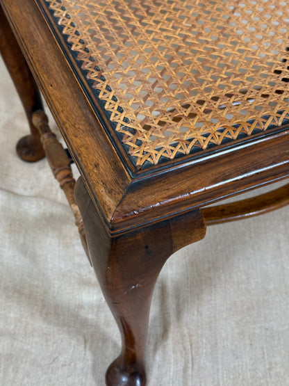 Antique Bergère style cane armchair and matching footstool with dark carved wooden frames and woven cane panels.