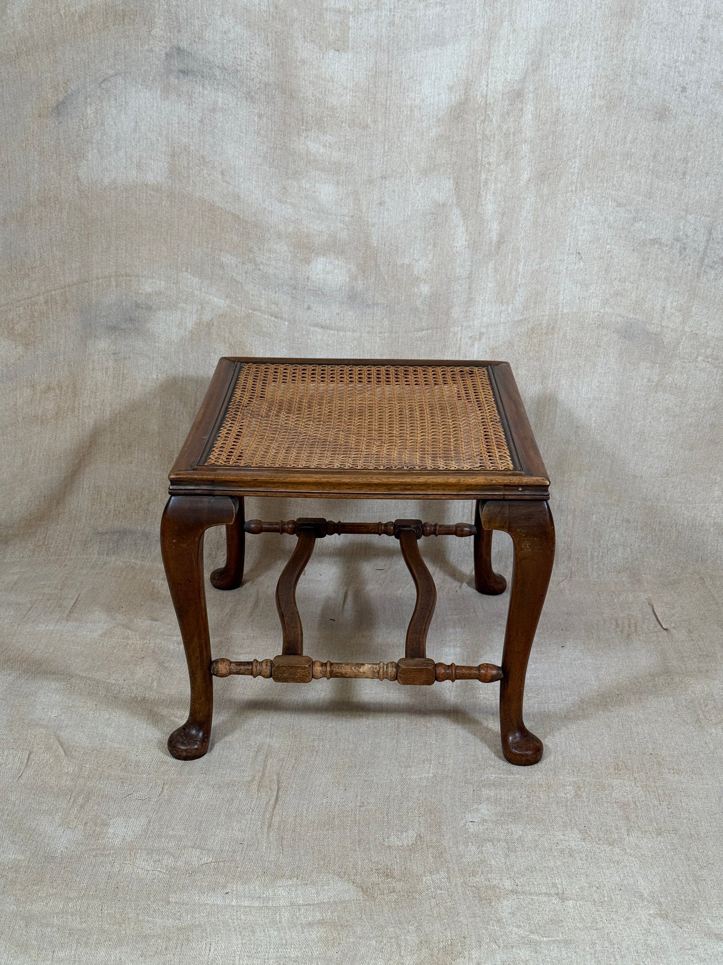 Antique Bergère style cane armchair and matching footstool with dark carved wooden frames and woven cane panels.