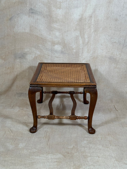 Antique Bergère style cane armchair and matching footstool with dark carved wooden frames and woven cane panels.