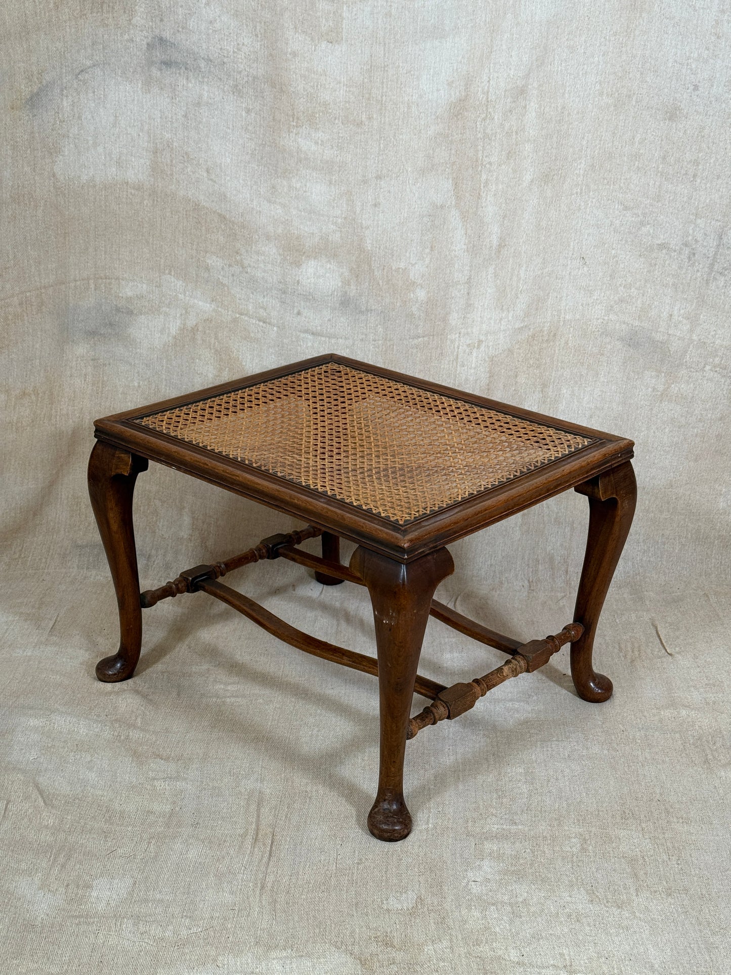Antique Bergère style cane armchair and matching footstool with dark carved wooden frames and woven cane panels.
