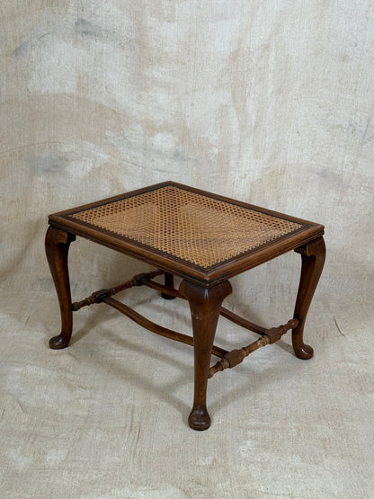 Antique Bergère style cane armchair and matching footstool with dark carved wooden frames and woven cane panels.