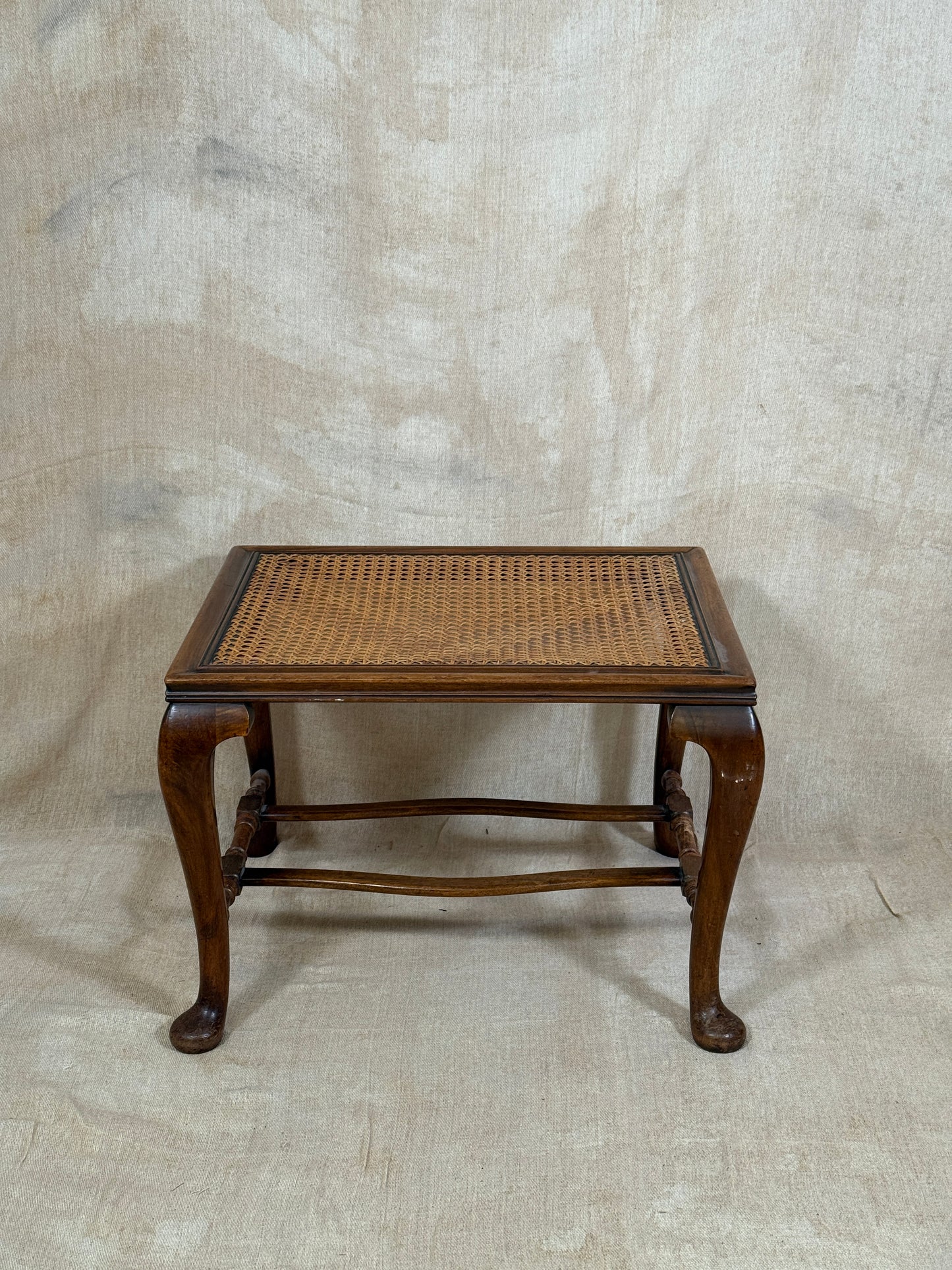 Antique Bergère style cane armchair and matching footstool with dark carved wooden frames and woven cane panels.