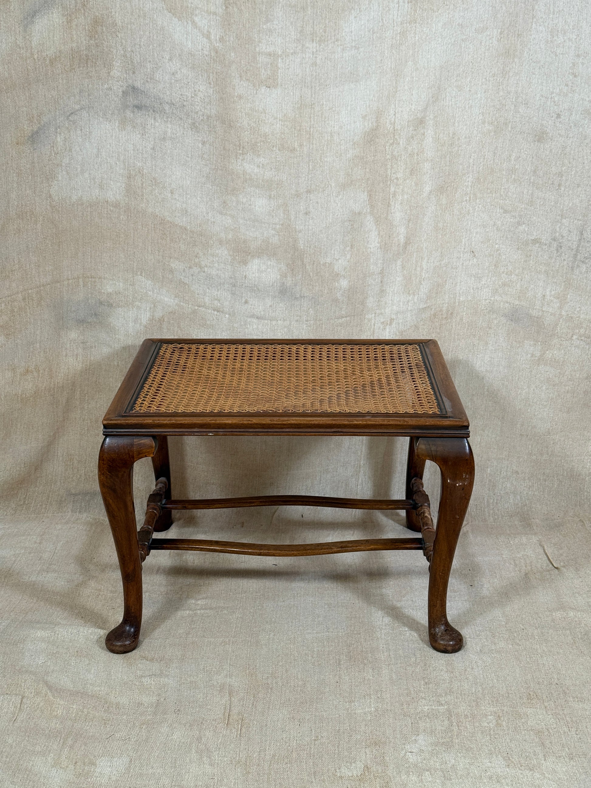 Antique Bergère style cane armchair and matching footstool with dark carved wooden frames and woven cane panels.