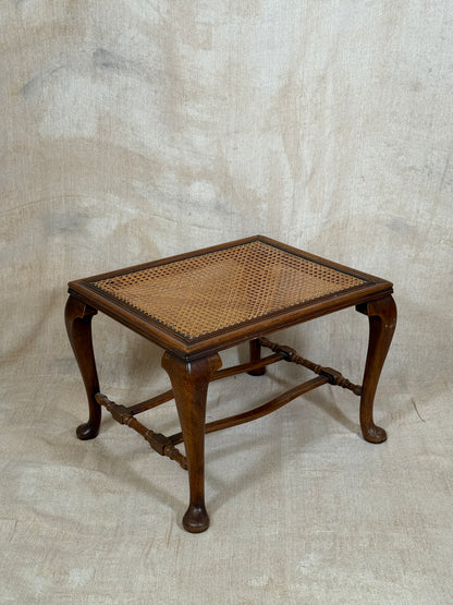 Antique Bergère style cane armchair and matching footstool with dark carved wooden frames and woven cane panels.