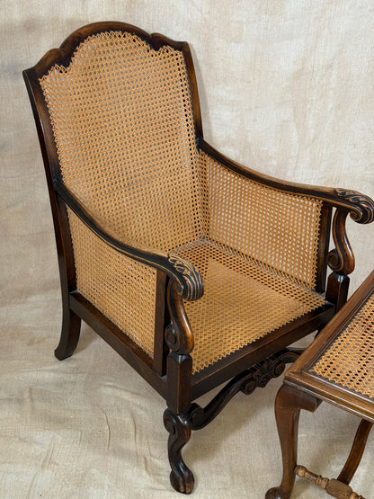 Antique Bergère style cane armchair and matching footstool with dark carved wooden frames and woven cane panels.