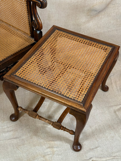 Antique Bergère style cane armchair and matching footstool with dark carved wooden frames and woven cane panels.
