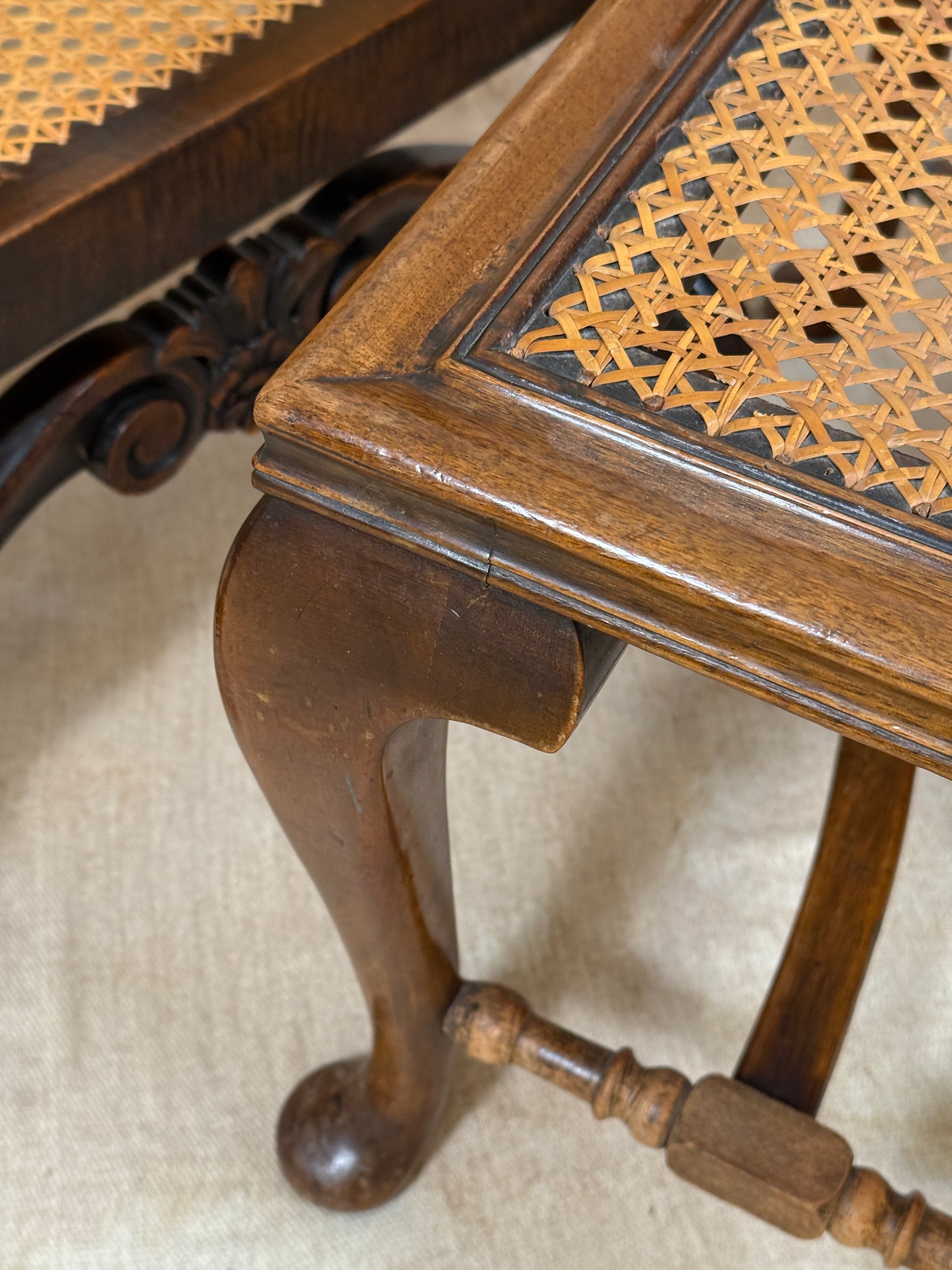 Antique Bergère style cane armchair and matching footstool with dark carved wooden frames and woven cane panels.