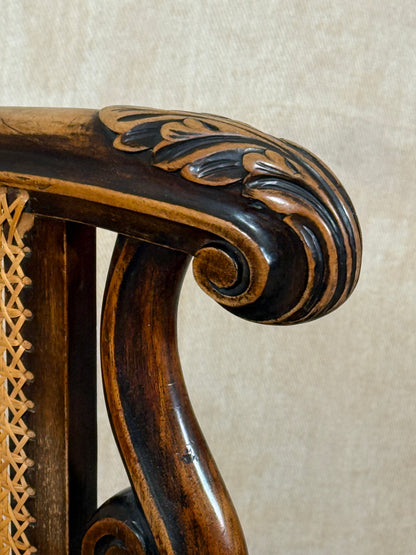 Antique Bergère style cane armchair and matching footstool with dark carved wooden frames and woven cane panels.