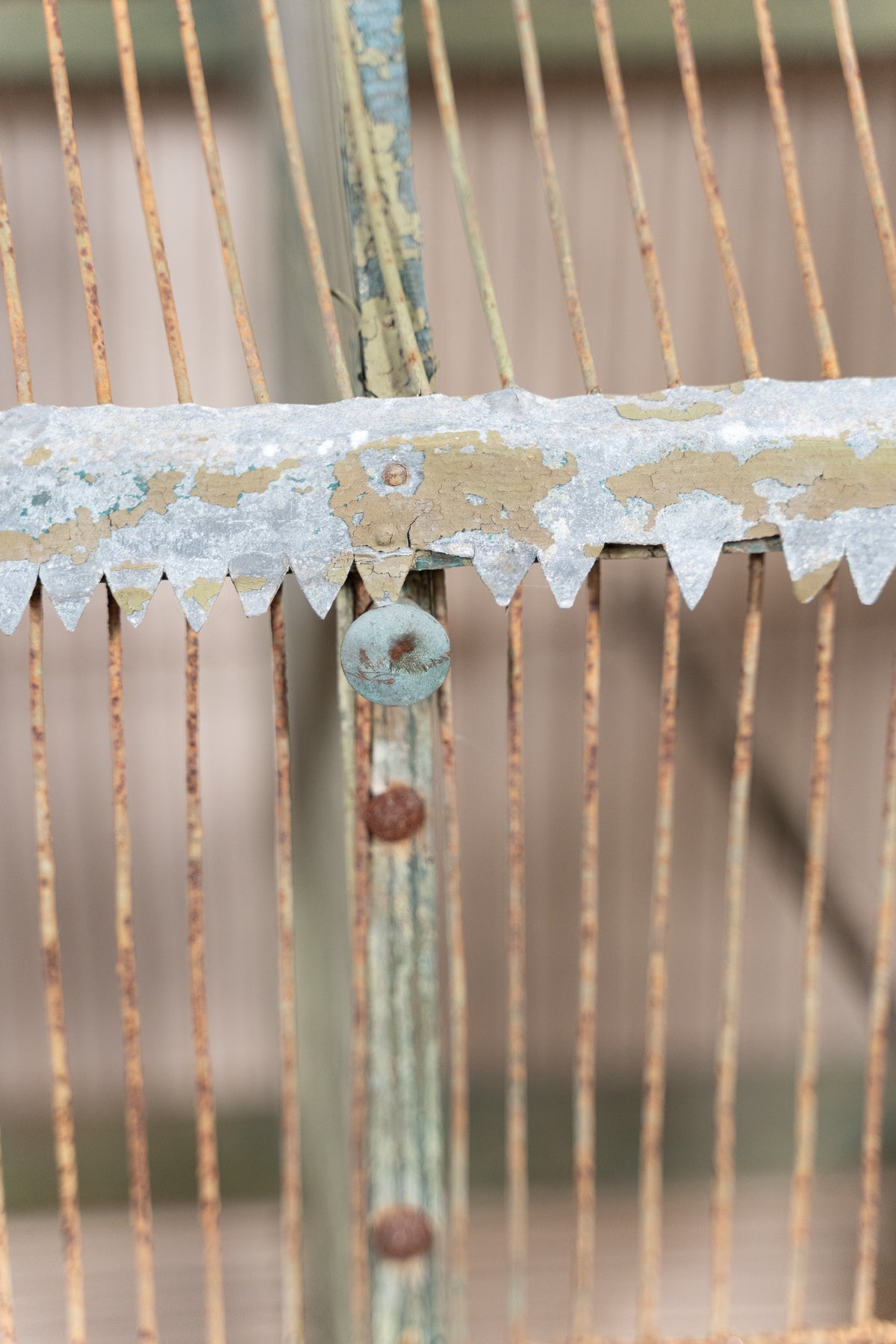 Vintage wooden birdcage with weathered green paint, decorative metal ridge detail, wire mesh panels and feeding troughs on both sides.
