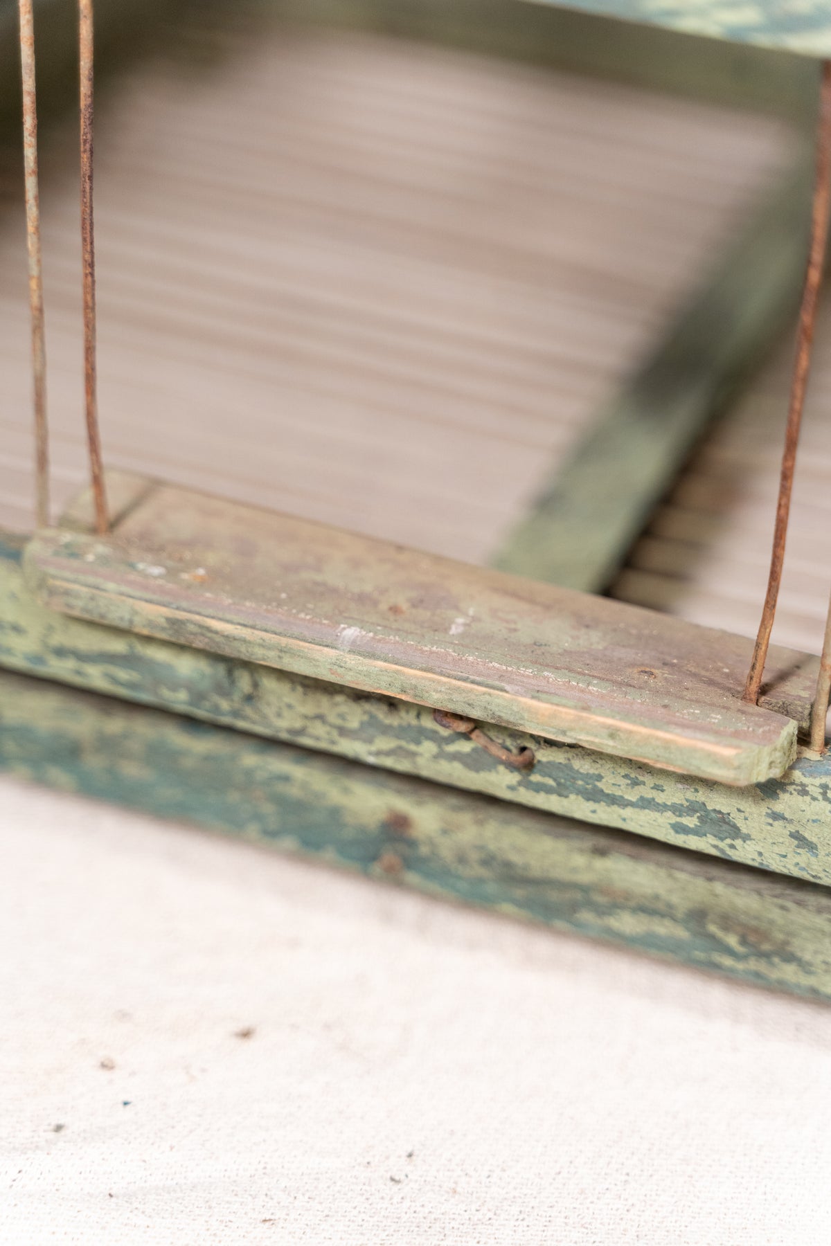 Vintage wooden birdcage with weathered green paint, decorative metal ridge detail, wire mesh panels and feeding troughs on both sides.