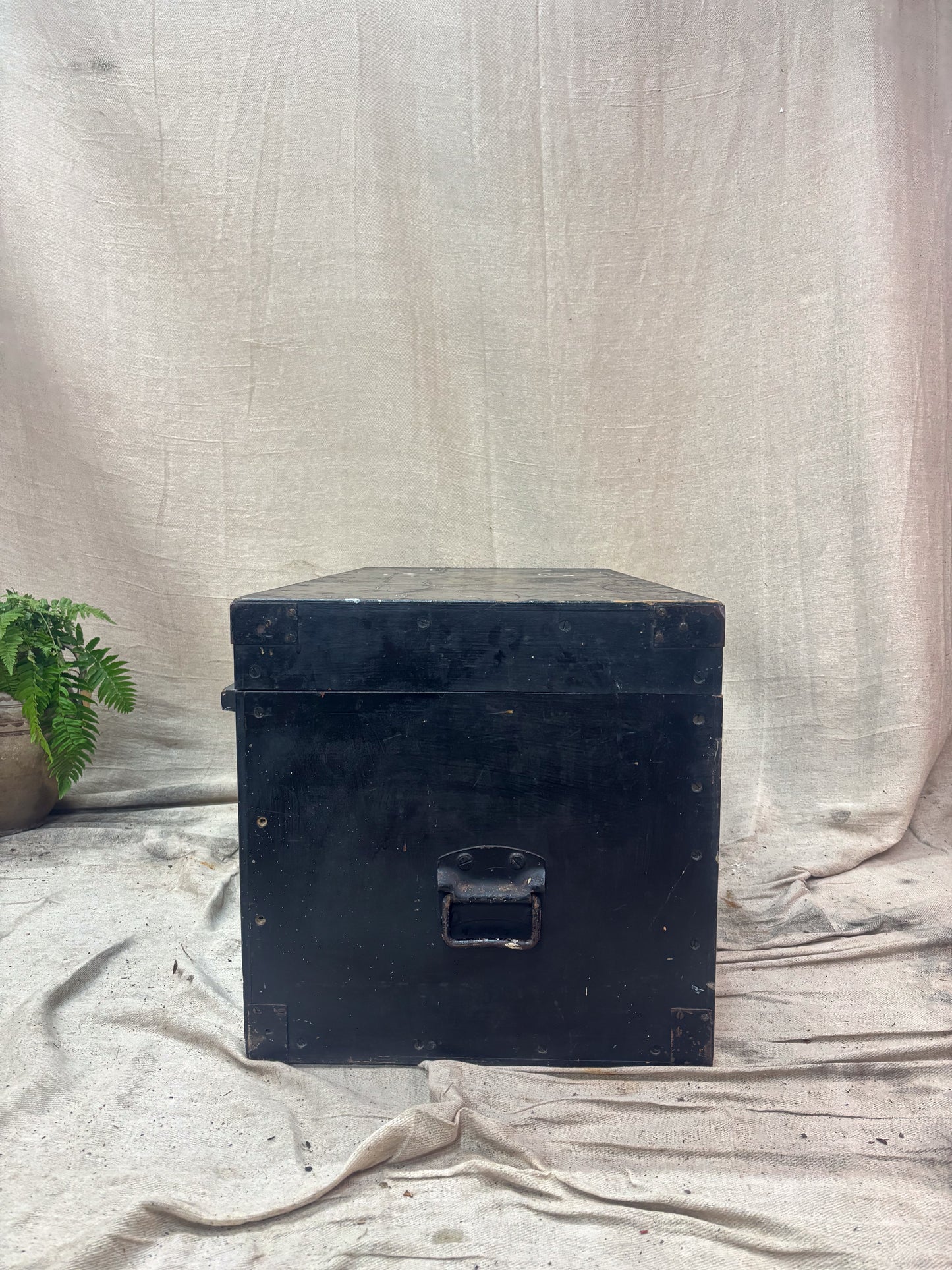Black wooden storage box on a wooden surface with a white fabric background