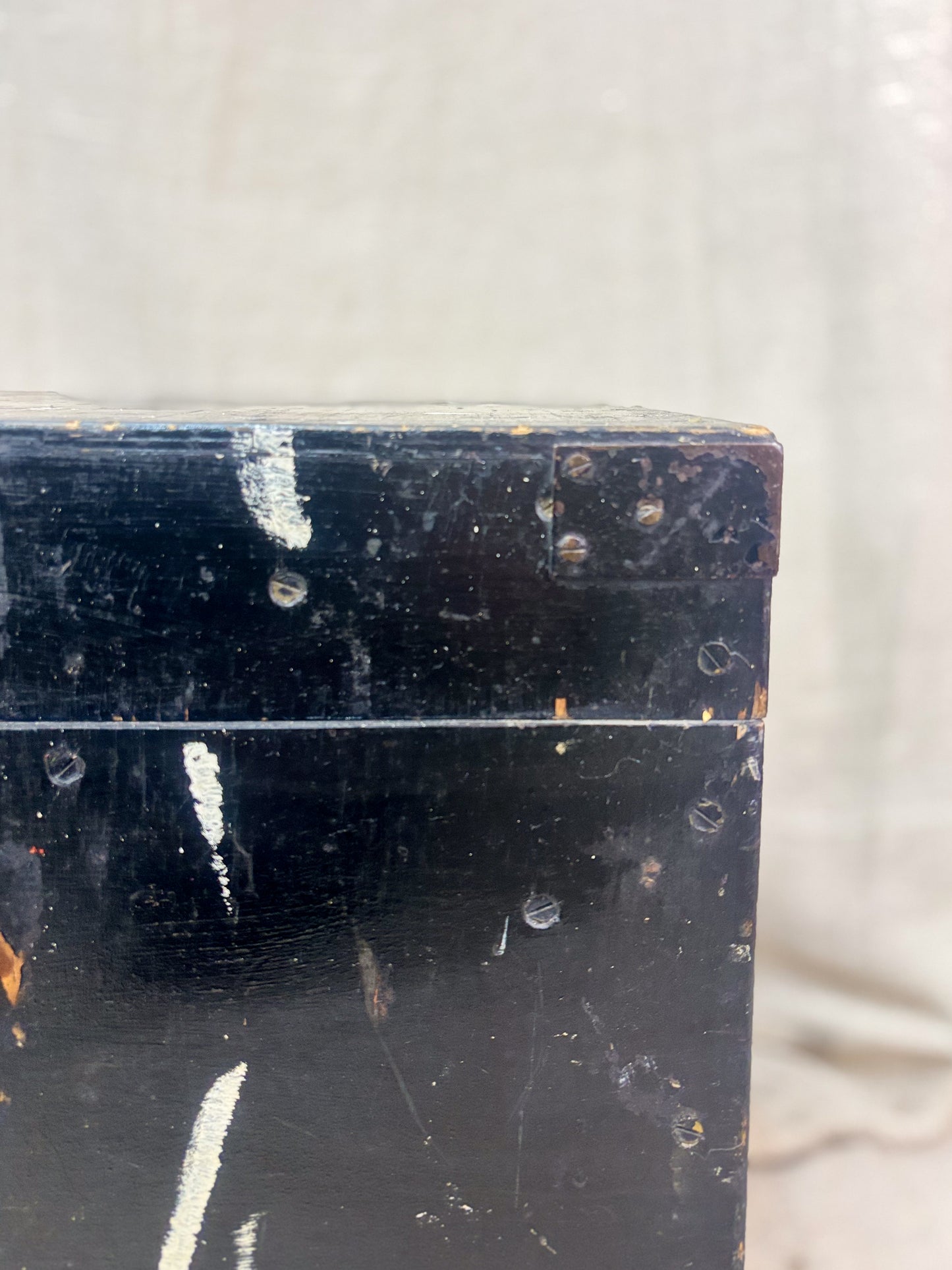 Close-up of a dark wooden box with visible wear and tear on a light gray background