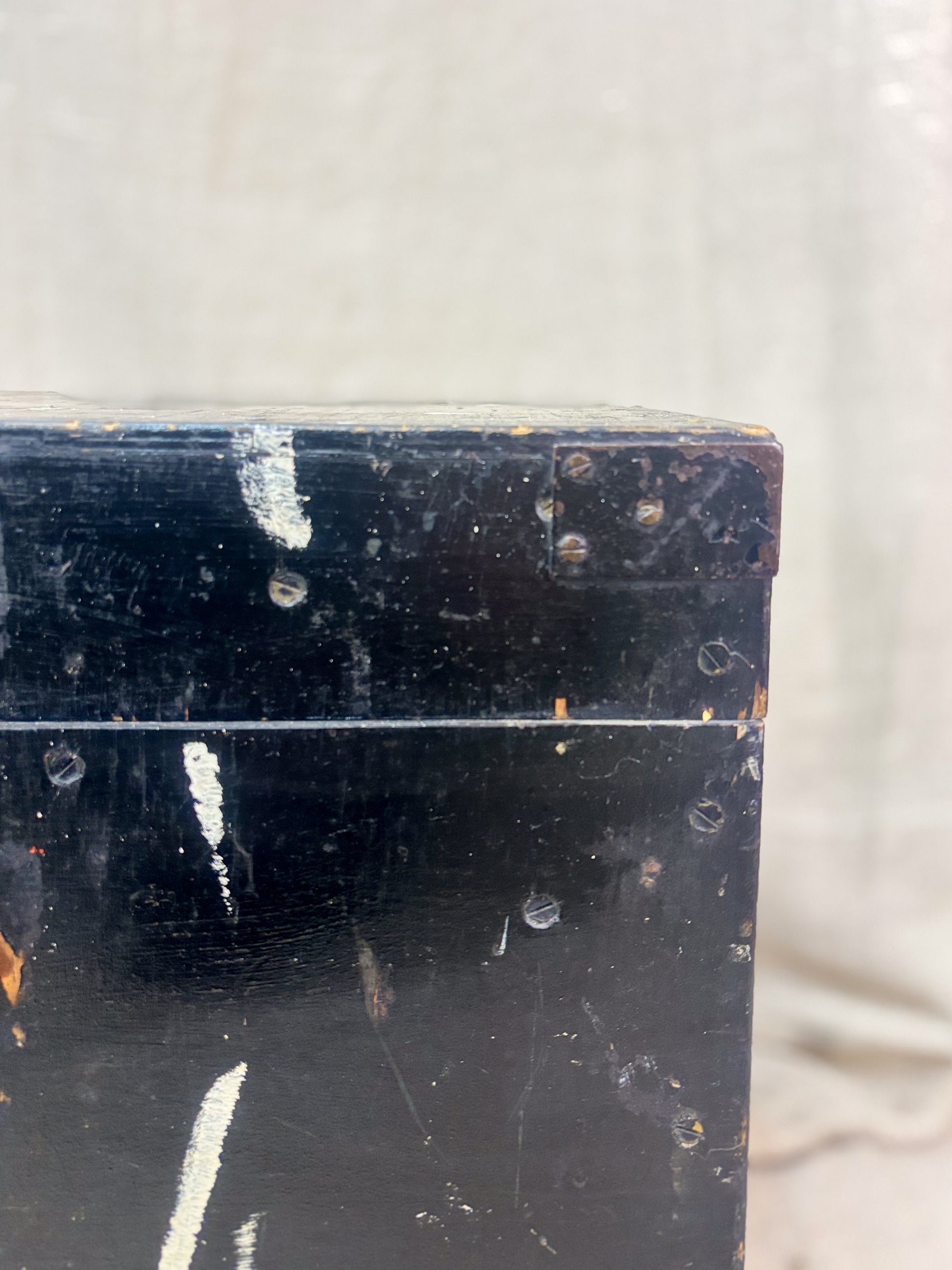 Close-up of a dark wooden box with visible wear and tear on a light gray background