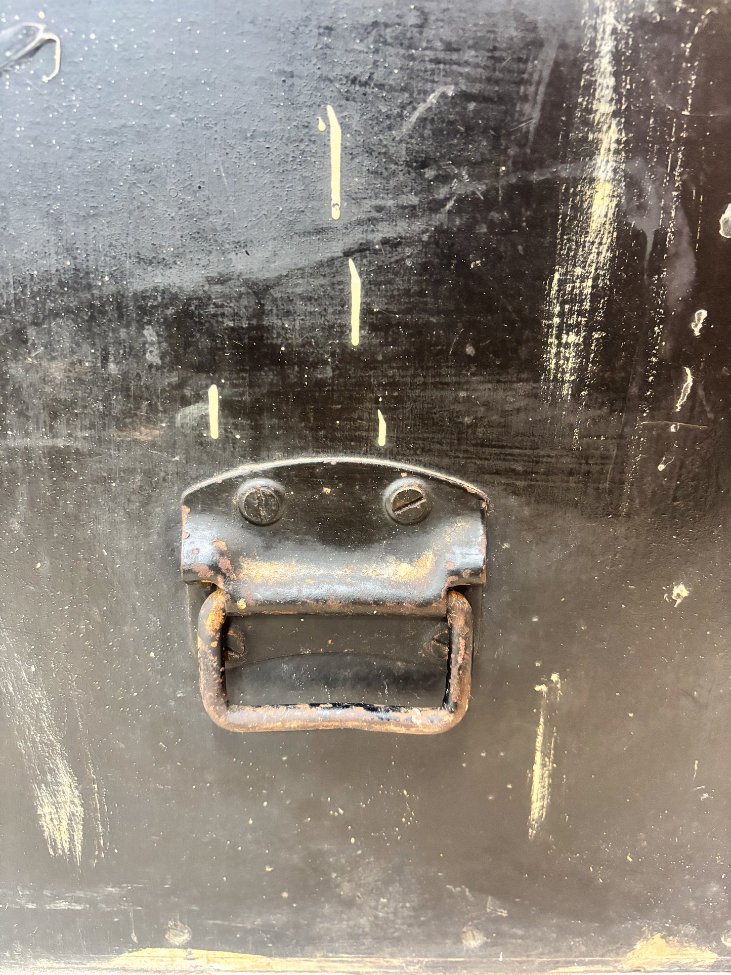 Rust-colored metal handle on a black surface with visible wear and tear.