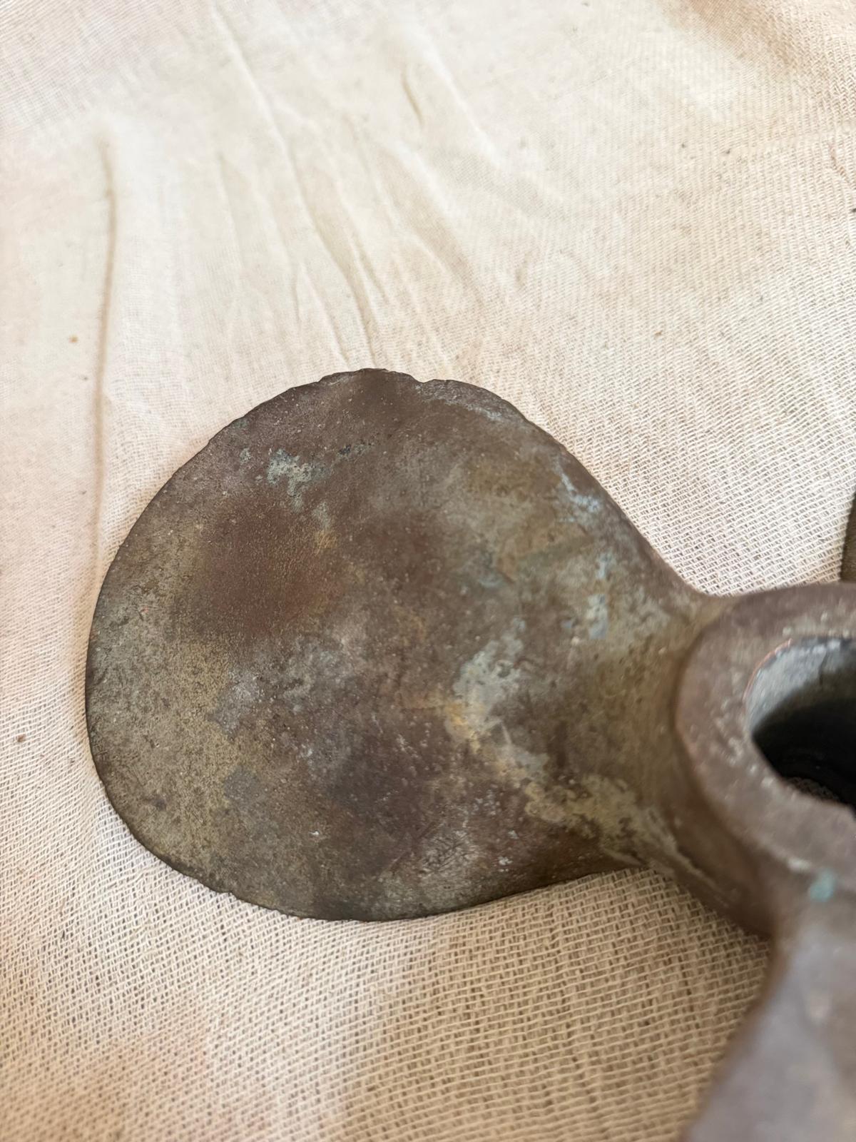 Bronze axe head on a beige fabric background