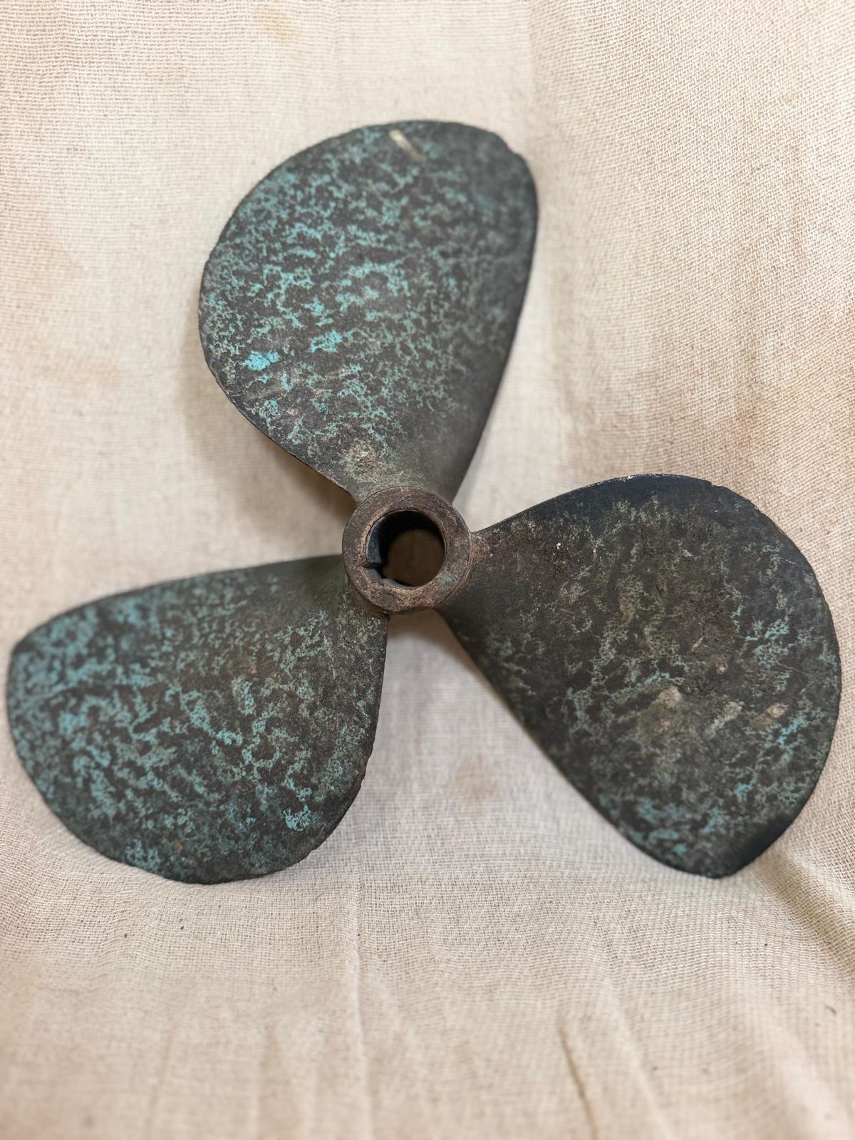 Rustic bronze propeller on a beige fabric background