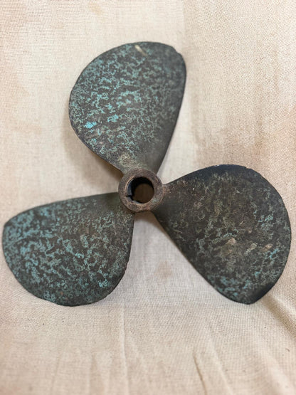 Rustic bronze propeller on a beige fabric background