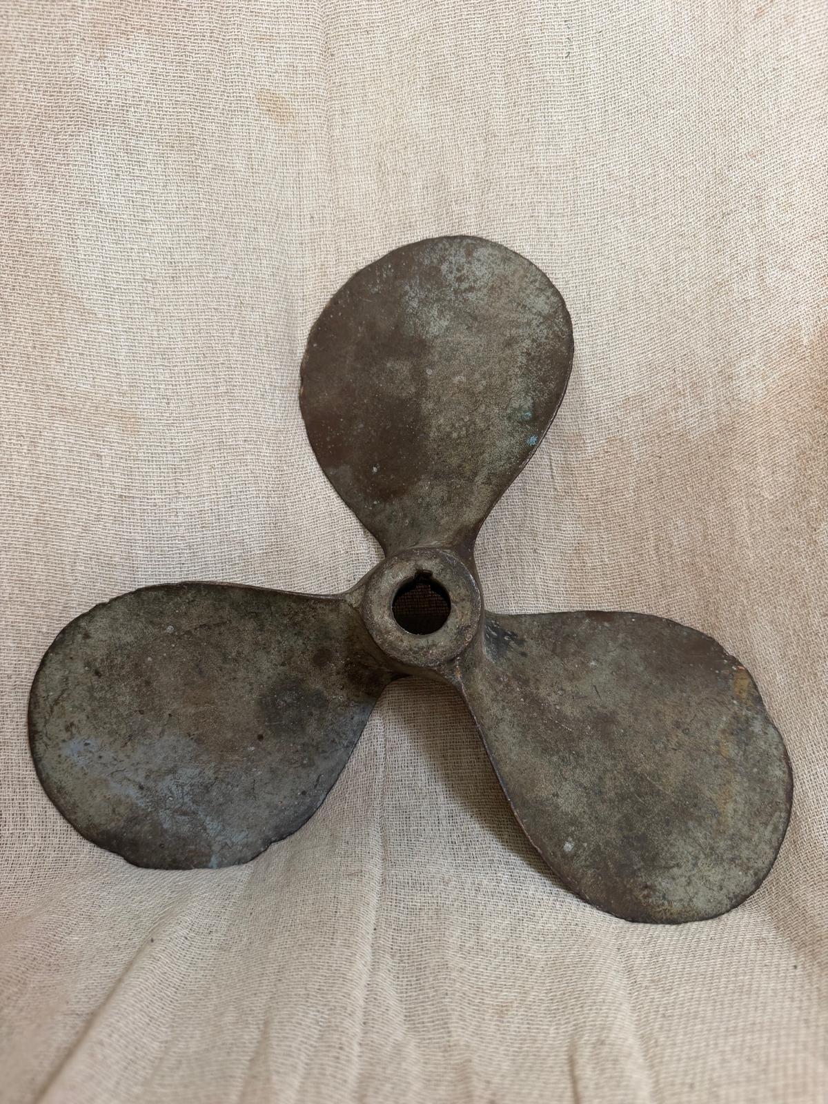 Vintage three-blade metal propeller on a beige fabric background