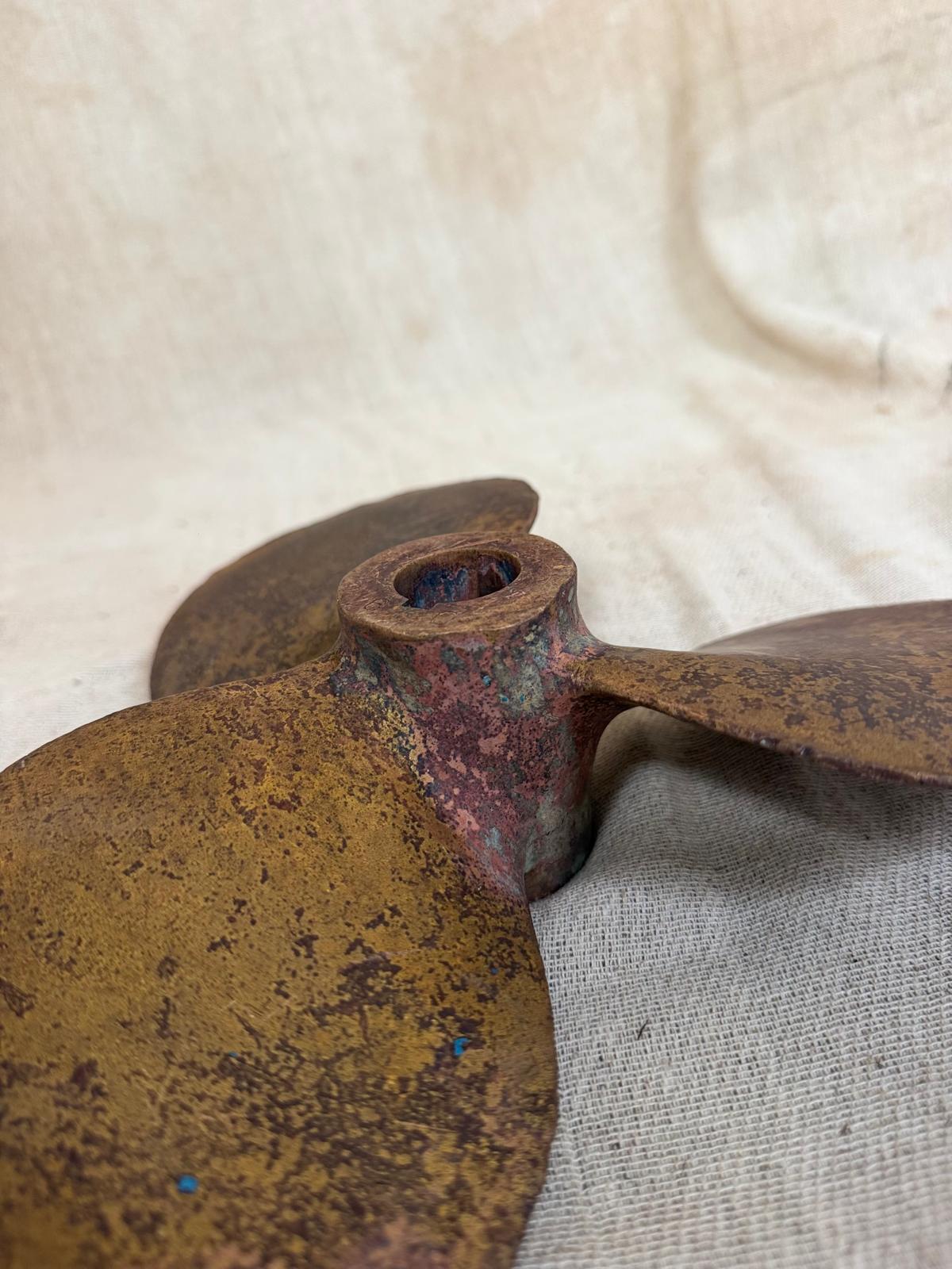 Rust-covered metal propeller on a textured fabric background