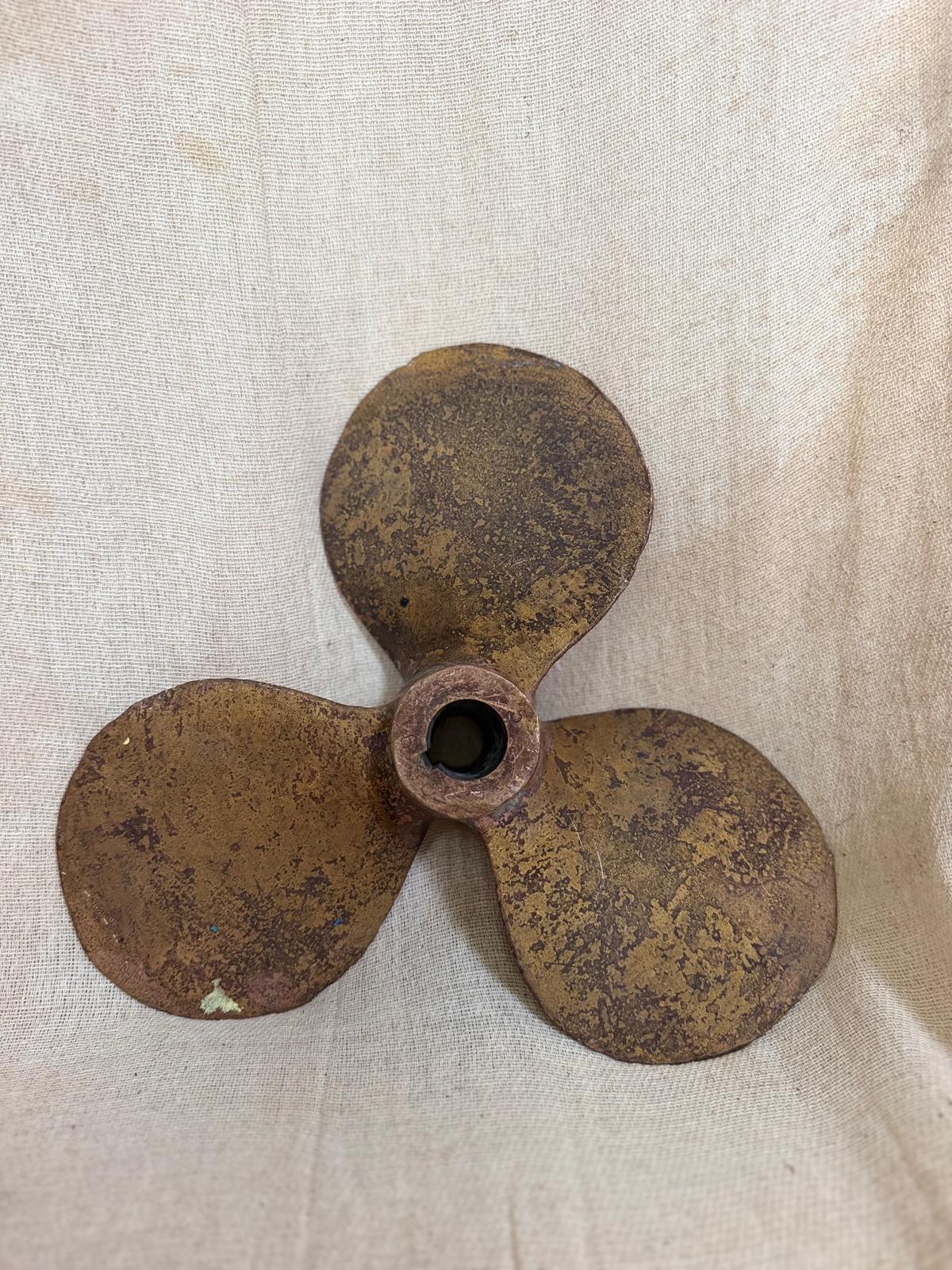 Rust-colored three-blade propeller on a beige fabric background