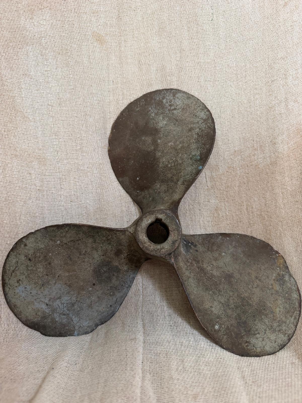 Vintage three-blade metal propeller on a beige fabric background