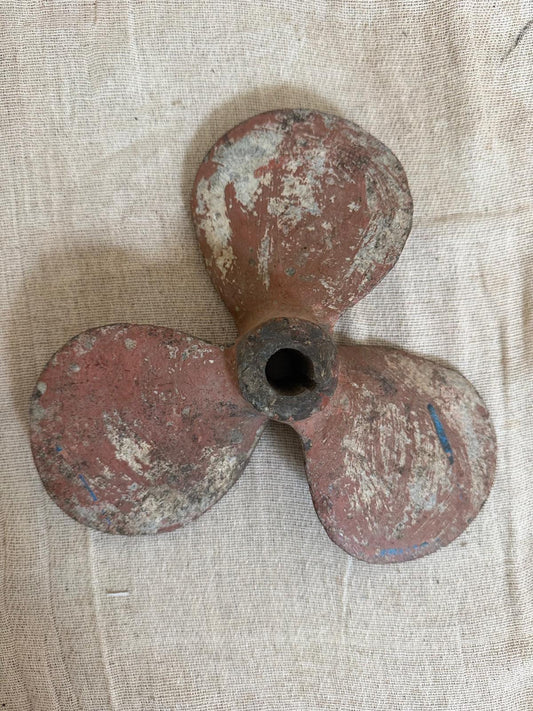 Rust-colored propeller on a textured beige background